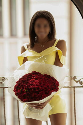Black Manchester escort in a yellow dress holding a boquet of flowers