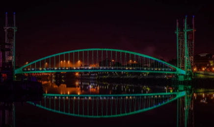 Night time photo of a lit up bridge in Manchester