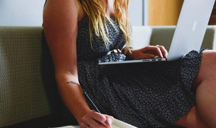 Woman in a summer dress working on a laptop