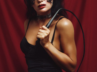 Masked BDSM woman in black dress holding a whip