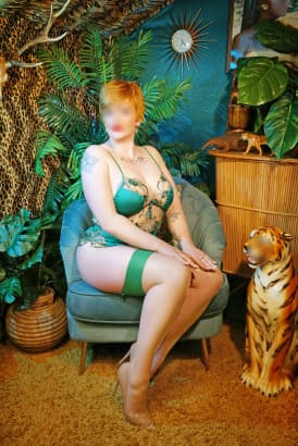 Ginger girl with cropped hair sitting next to a statue of a leopard