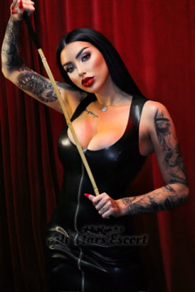 Busty black haired fetish Mistress holding a wooden cane